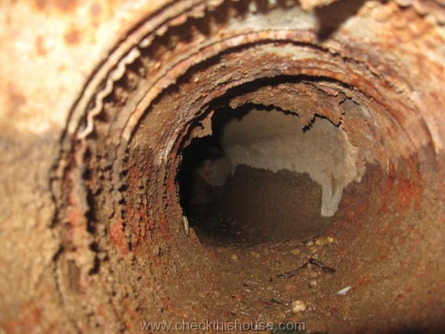 Musty odor from a forced air heatings system - interior of the heavily corroded metal air duct installed under the concrete slab