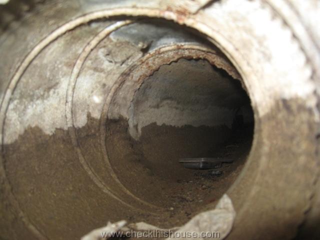 Musty smell from air ducts - high water line visible on interior walls of an air duct installed under the concrete floor.