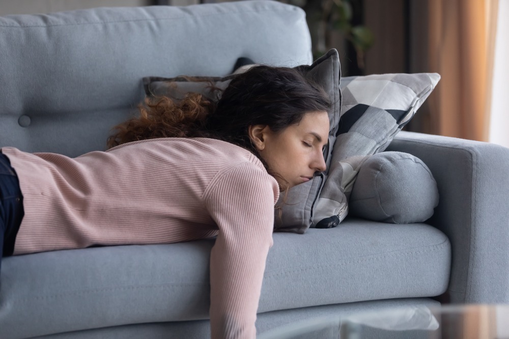 tired millennial female fall asleep on couch at home